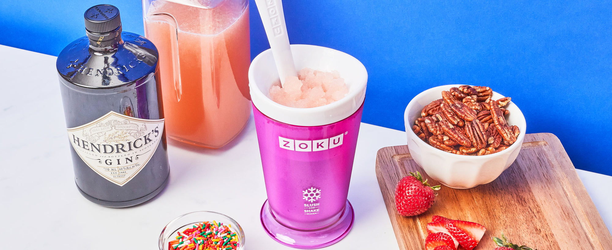 An image of a ZOKU Slush & Shake maker containing a strawberry-colored slushy. Various topics are arranged around the slush maker.