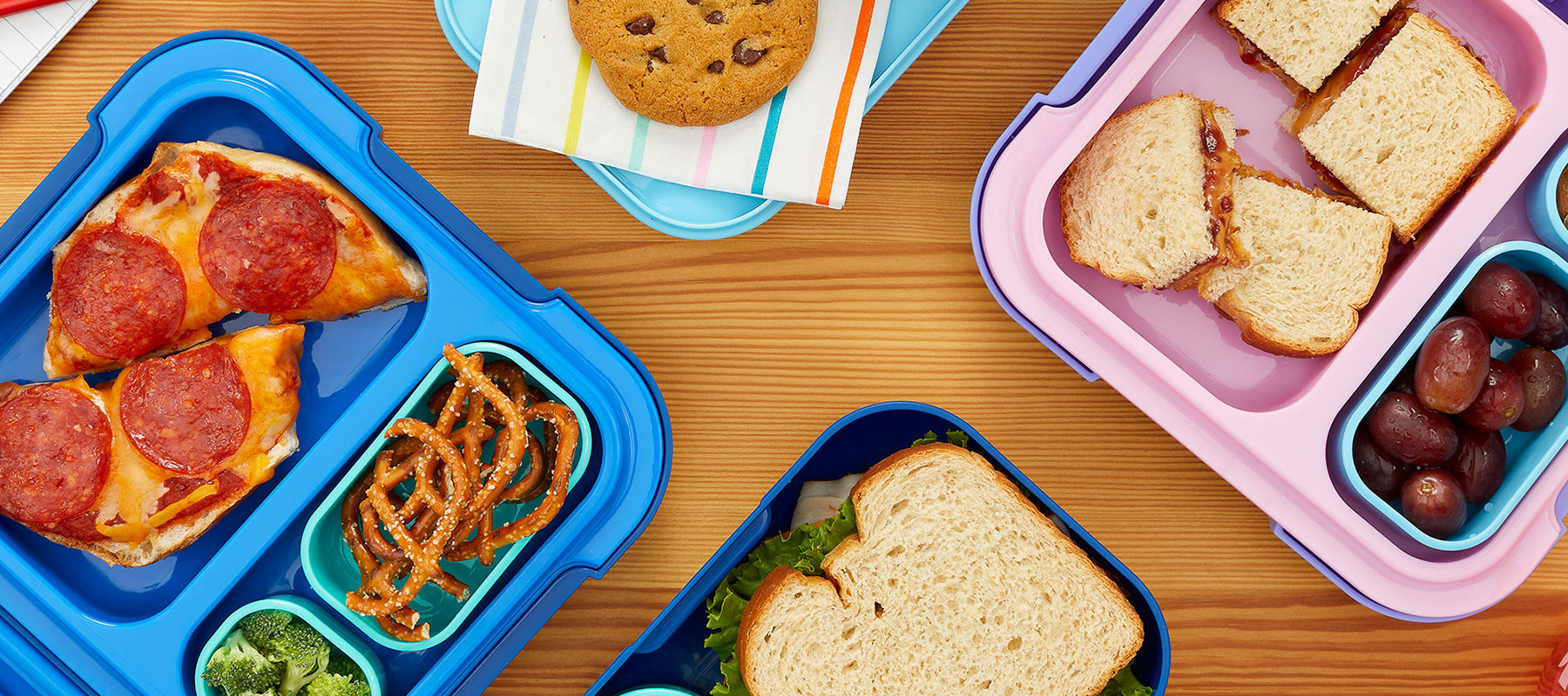  A close-up of ZOKU Kids Neat Bento in Pink and Blue, showcasing various food combinations in the lunch containers.