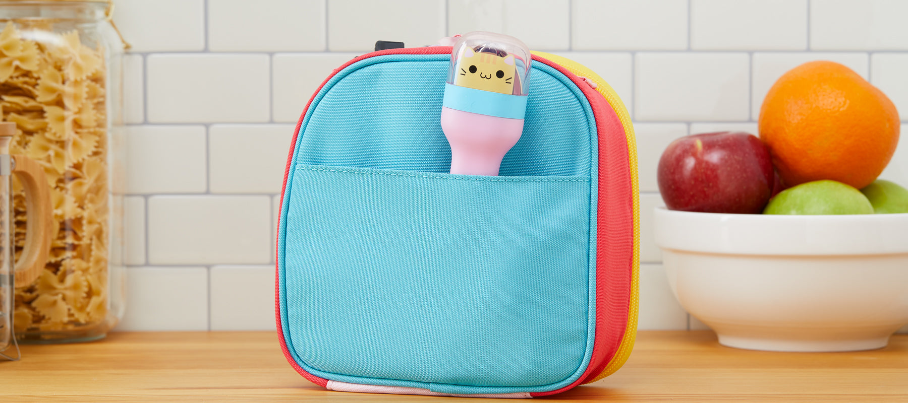  The ZOKU Kids Pocket Utensil in the Kitty pattern is conveniently stored inside a blue lunch bag, atop a wooden kitchen countertop.