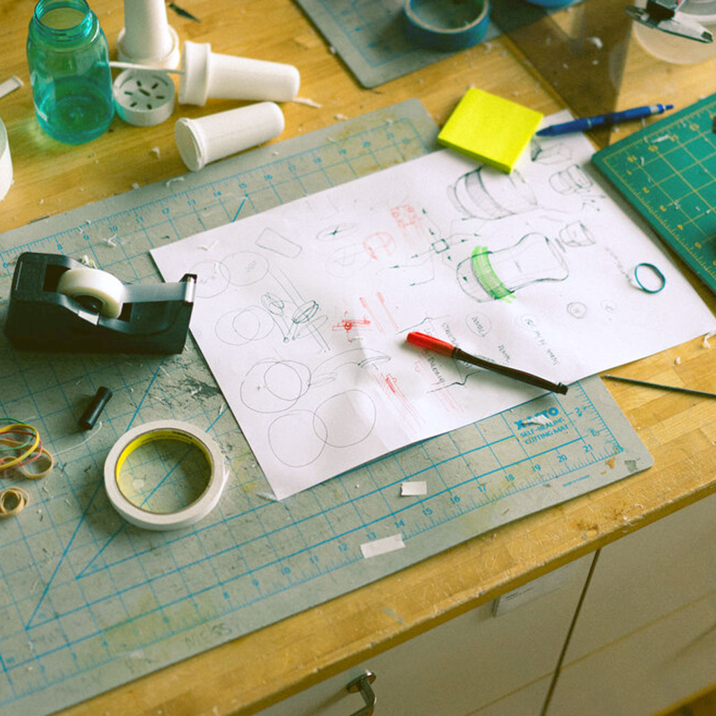 Product design sketches, tape, prototypes, sticky notes, and rulers strewn across the ZOKU design team workspace.